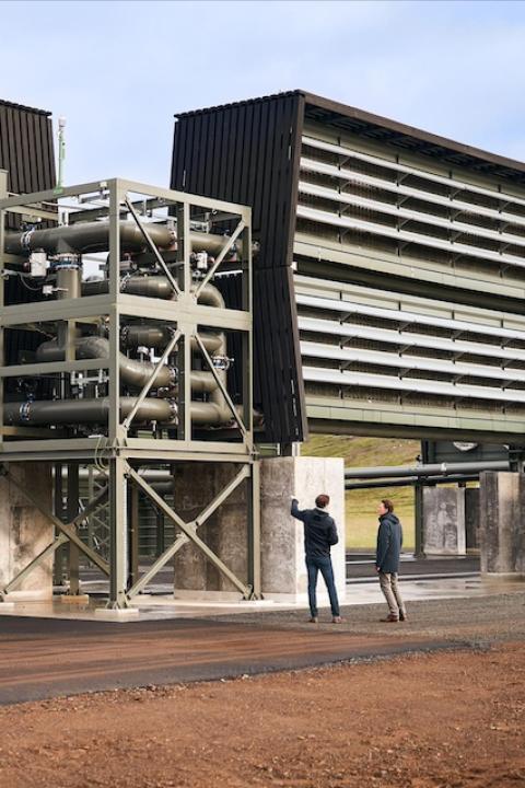 Two people standing next to carbon capture machinery — once carbon is captured it can be turned into useful products